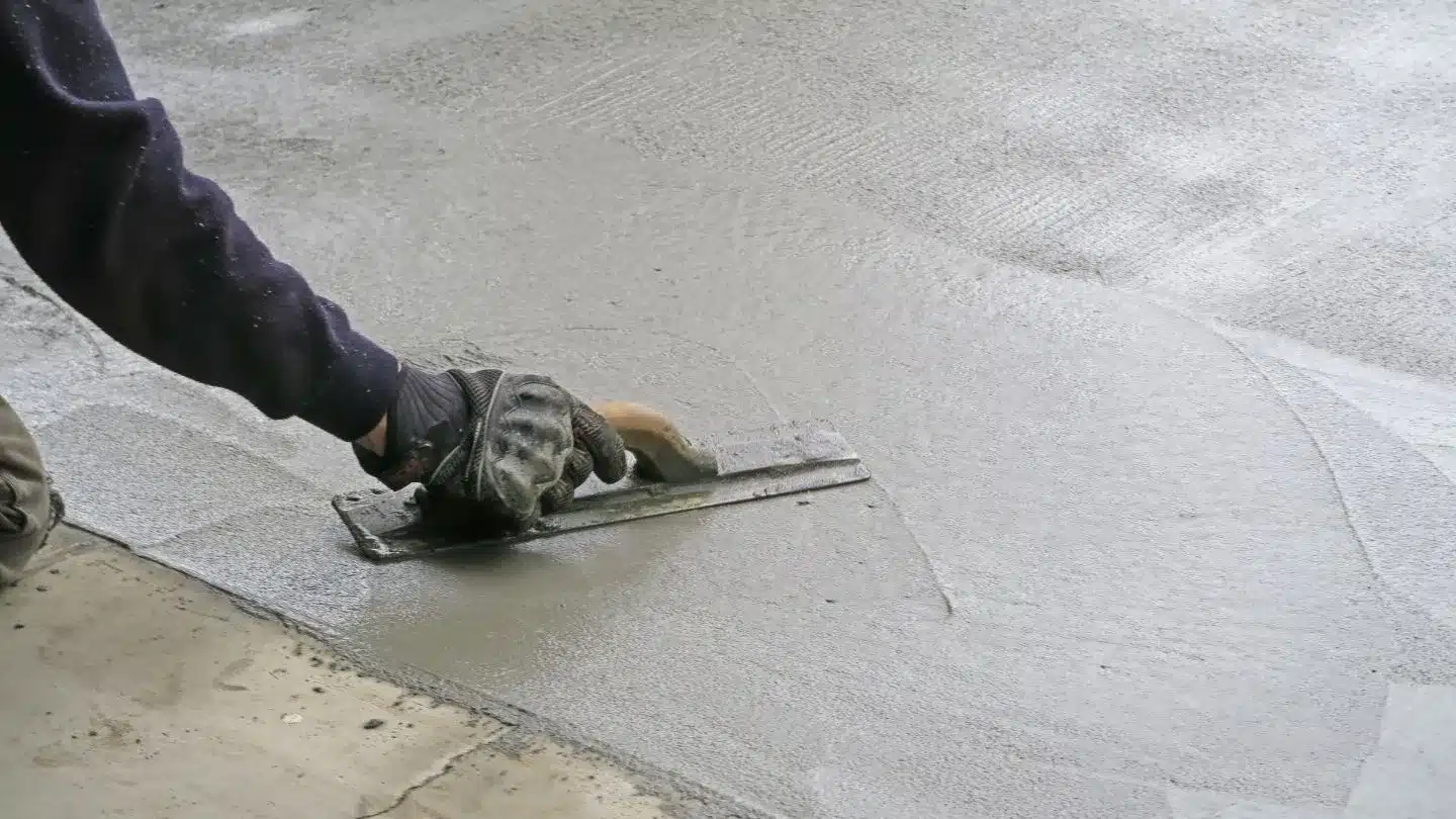 Worker Smoothing Fresh Concrete Surface With Hand Trowel 