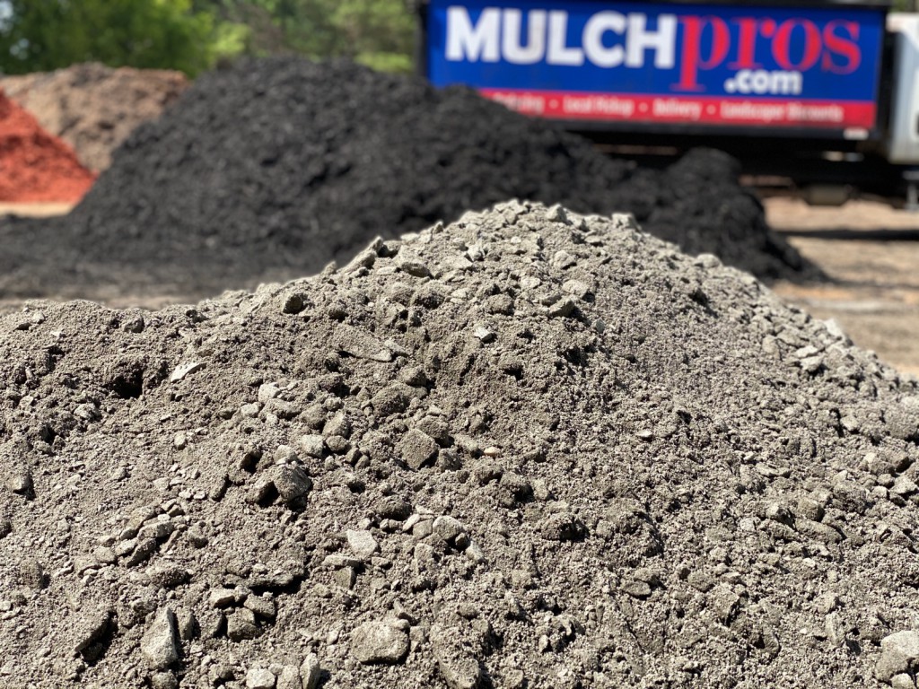A crusher run gravel pile in focus with the MulchPros truck behind.