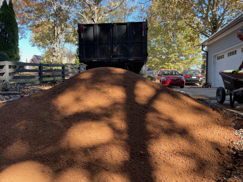 Red fill dirt delivered at a driveway with the MulchPros box truck behind.
